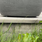 Close-up of the gap beneath a grey plant pot on wooden decking